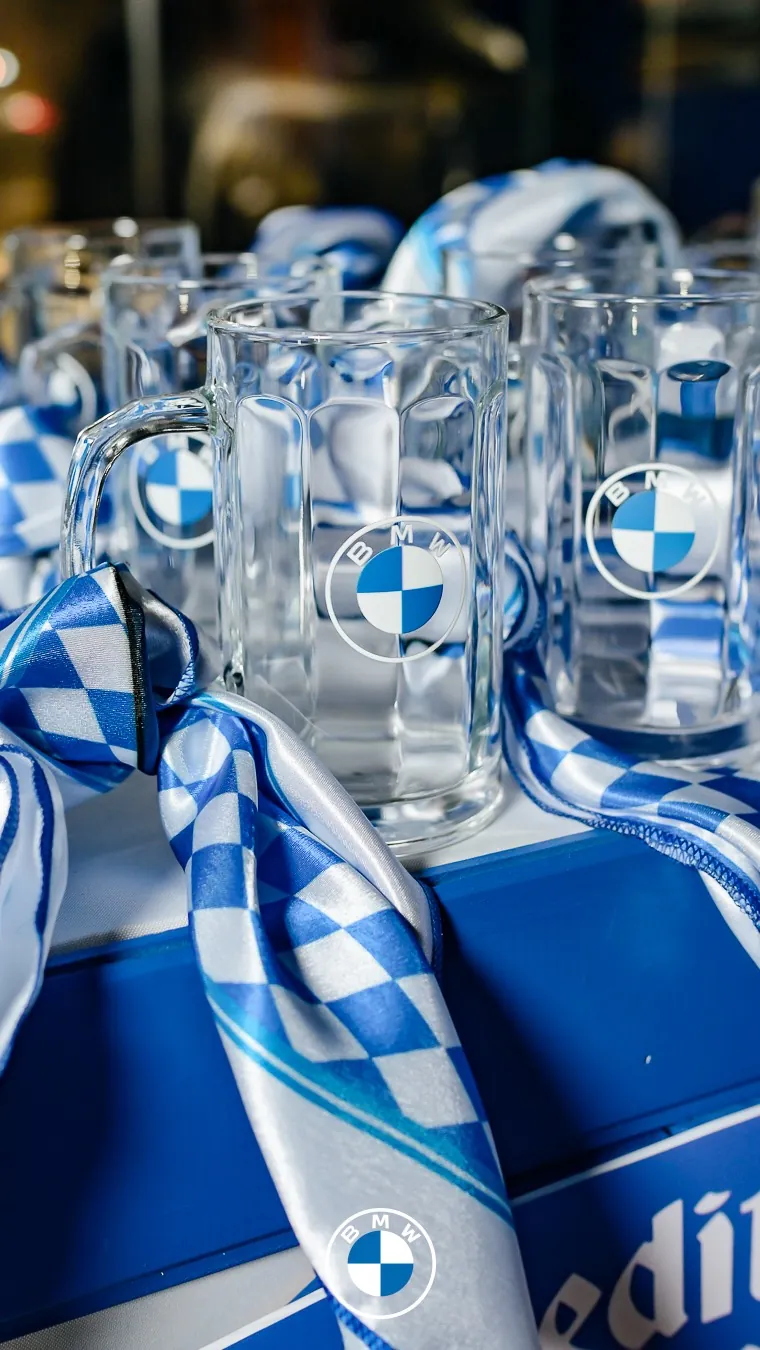 Jarras de cerveza con el logo de BMW y pañuelos bávaros azules y blancos.