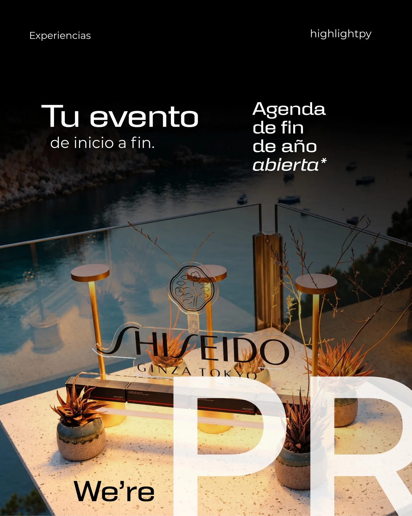 Mesa de Shiseido con lámparas doradas y vista a una bahía al atardecer.