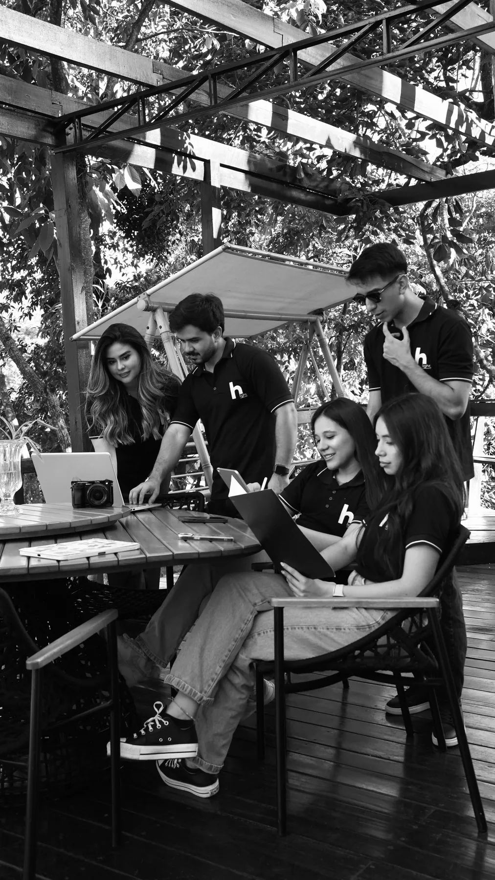 El equipo de Highlight trabaja alrededor de una mesa bajo una pérgola, en blanco y negro.